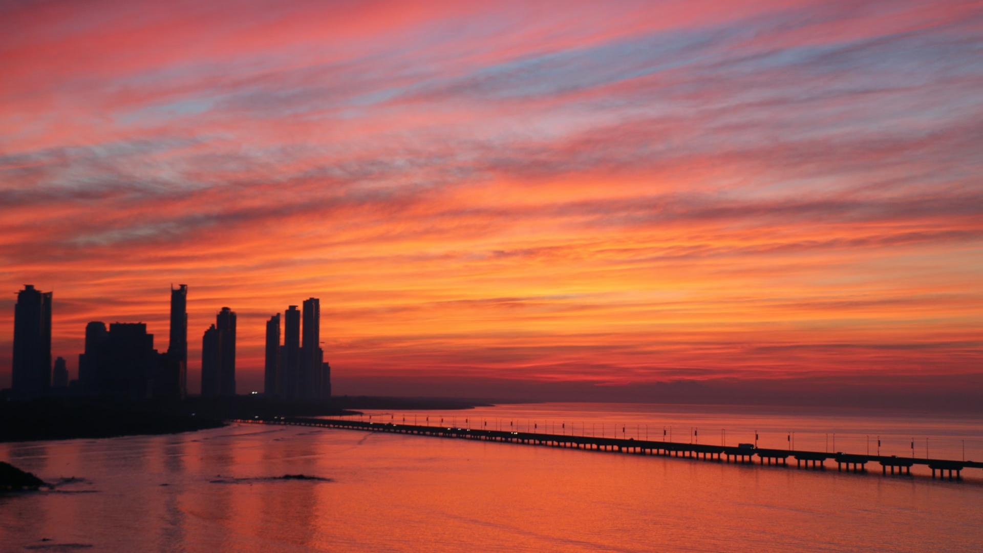 silhouette of buildings near body of water during dawn